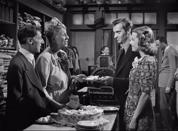 Movie still from “The Southerner” (1945), directed by Jean Renoir – A group of people standing around a table with food on top of it; Medium shot, Over the shoulder angle