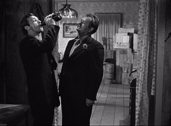 Movie still from “The Southerner” (1945), directed by Jean Renoir – Two men in suits are standing in a living room; Medium shot, Low angle