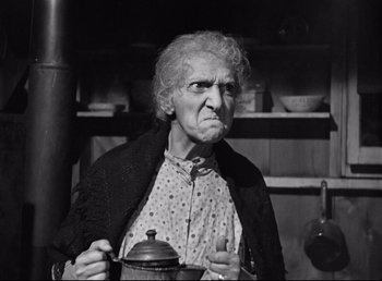 An old woman is holding a tea pot in her hands