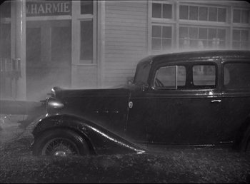 Movie still from “The Southerner” (1945), directed by Jean Renoir – An old car is parked in front of a building; Wide shot, High angle