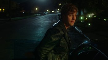 Movie still from “The Space Between” (2021), directed by Rachel Winter – A young man standing next to a car at night; Close Up shot, Over the shoulder angle