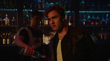 Movie still from “The Space Between” (2021), directed by Rachel Winter – A man in a leather jacket is holding a bottle; Close Up shot, Over the shoulder angle