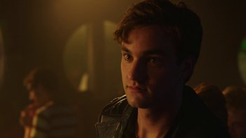Movie still from “The Space Between” (2021), directed by Rachel Winter – A person wearing a leather jacket; Close Up shot, Over the shoulder angle