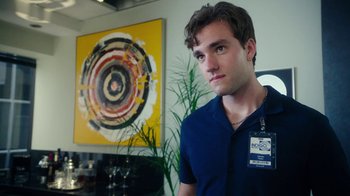 Movie still from “The Space Between” (2021), directed by Rachel Winter – A man with a badge around his neck; Close Up shot, Over the shoulder angle