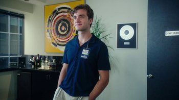 Movie still from “The Space Between” (2021), directed by Rachel Winter – A man standing in front of a painting in a room; Medium shot, Low angle