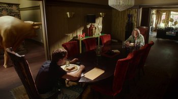 Movie still from “The Space Between” (2021), directed by Rachel Winter – A group of people sitting at a table eating dinner; Wide shot, Over the shoulder angle