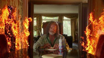 Movie still from “The Space Between” (2021), directed by Rachel Winter – A man sitting at a dinner table with a plate in his hand; Medium shot, Low angle