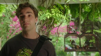 Movie still from “The Space Between” (2021), directed by Rachel Winter – A young man with a bird on a perch in the background; Close Up shot, Over the shoulder angle