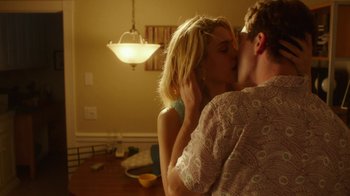 Movie still from “The Space Between” (2021), directed by Rachel Winter – A man and a woman kissing in a living room; Medium shot, Low angle