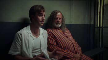 Movie still from “The Space Between” (2021), directed by Rachel Winter – Two men sitting next to each other in a room; Medium shot, Over the shoulder angle