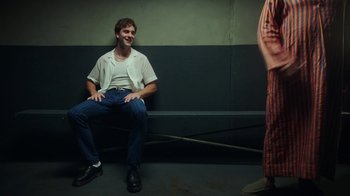 Movie still from “The Space Between” (2021), directed by Rachel Winter – A man sitting on a bench next to another man; Medium shot, Over the shoulder angle