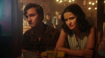 Movie still from “The Space Between” (2021), directed by Rachel Winter – A man and a woman sitting next to each other at a table; Close Up shot, Over the shoulder angle
