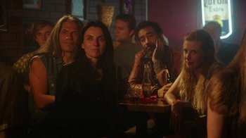 Movie still from “The Space Between” (2021), directed by Rachel Winter – A group of people sitting at a table with drinks; Medium shot, High angle