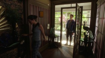 Movie still from “The Space Between” (2021), directed by Rachel Winter – Two people standing in front of an open front door; Wide shot, Over the shoulder angle