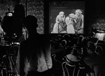 Movie still from “The Spiral Staircase” (1946), directed by Robert Siodmak – People are sitting in chairs in front of a large screen; Wide shot, Over the shoulder angle