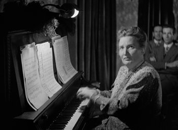 Movie still from “The Spiral Staircase” (1946), directed by Robert Siodmak – An older woman sitting at a piano with sheet music on it; Medium shot, Low angle