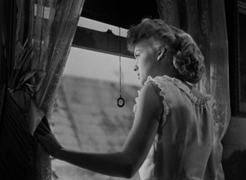 Movie still from “The Spiral Staircase” (1946), directed by Robert Siodmak – A black and white photo of a woman looking out of a window; Medium shot, Low angle