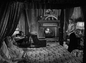 Movie still from “The Spiral Staircase” (1946), directed by Robert Siodmak – A bedroom scene with a fireplace and a bed in the background; Wide shot, High angle