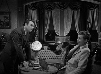 Movie still from “The Spiral Staircase” (1946), directed by Robert Siodmak – Two men in suits are sitting at a table; Medium shot, Over the shoulder angle
