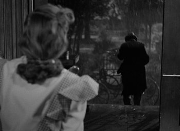 Movie still from “The Spiral Staircase” (1946), directed by Robert Siodmak – Two people walking in the rain on a bridge; Medium shot, Over the shoulder angle