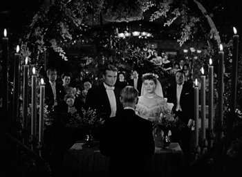 Movie still from “The Spiral Staircase” (1946), directed by Robert Siodmak – A black and white photo of a couple getting married; Wide shot, High angle
