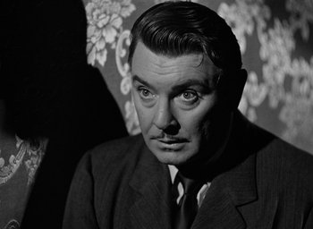 Movie still from “The Spiral Staircase” (1946), directed by Robert Siodmak – An older man wearing a suit and tie in front of a wall; Close Up shot, Over the shoulder angle