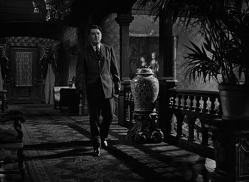 Movie still from “The Spiral Staircase” (1946), directed by Robert Siodmak – A black and white photo of a man in a suit; Wide shot, Low angle