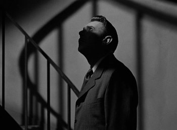 Movie still from “The Spiral Staircase” (1946), directed by Robert Siodmak – A black and white photo of a man in a suit; Medium shot, Low angle
