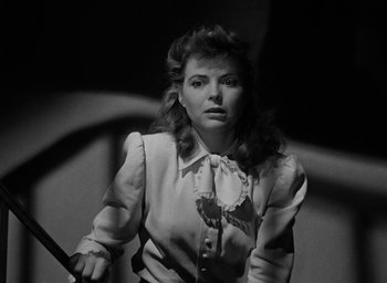 Movie still from “The Spiral Staircase” (1946), directed by Robert Siodmak – A black and white photo of a woman holding a sword; Close Up shot, Low angle