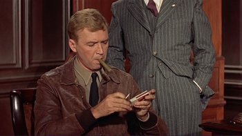 Movie still from “The Spirit of St. Louis” (1957), directed by Billy Wilder – A man smoking a cigarette while looking at a cell phone; Medium shot, Over the shoulder angle
