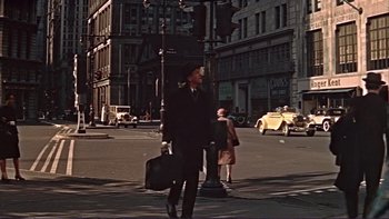 Movie still from “The Spirit of St. Louis” (1957), directed by Billy Wilder – A man walking across a street holding a briefcase; Wide shot, Low angle