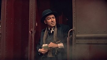 Movie still from “The Spirit of St. Louis” (1957), directed by Billy Wilder – A man wearing a hat and holding a cell phone in his hand; Medium shot, Low angle