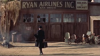 Movie still from “The Spirit of St. Louis” (1957), directed by Billy Wilder – A woman in a top hat is walking down the street; Wide shot, Low angle