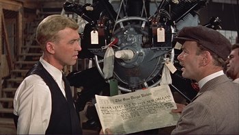 Movie still from “The Spirit of St. Louis” (1957), directed by Billy Wilder – A man holding a newspaper in front of two other men; Close Up shot, Over the shoulder angle