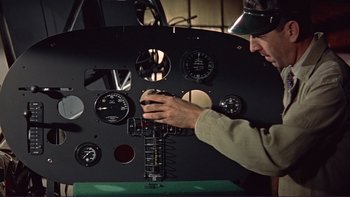 Movie still from “The Spirit of St. Louis” (1957), directed by Billy Wilder – A man working on an instrument panel of an airplane; Medium shot, Overhead angle