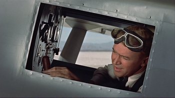 Movie still from “The Spirit of St. Louis” (1957), directed by Billy Wilder – A man wearing goggles looking out of an airplane window; Medium shot, Low angle