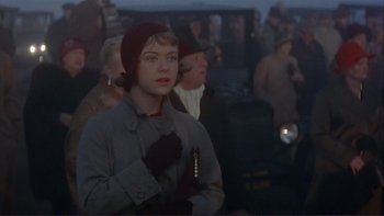 Movie still from “The Spirit of St. Louis” (1957), directed by Billy Wilder – A woman in a gray coat and a red hat is standing in front of a group of people; Medium shot, Over the shoulder angle