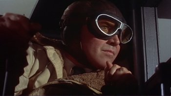 Movie still from “The Spirit of St. Louis” (1957), directed by Billy Wilder – A man wearing a helmet and goggles while sitting in an airplane; Close Up shot, Low angle