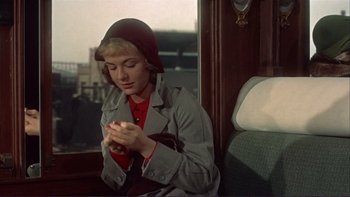 Movie still from “The Spirit of St. Louis” (1957), directed by Billy Wilder – A woman sitting on a train looking at her cell phone; Medium shot, High angle
