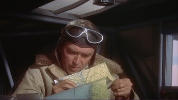 Movie still from “The Spirit of St. Louis” (1957), directed by Billy Wilder – An older man wearing a helmet and goggles looking at a map; Close Up shot, High angle