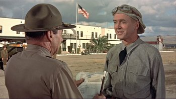 Movie still from “The Spirit of St. Louis” (1957), directed by Billy Wilder – A man in a hat is talking to another man in a uniform; Medium shot, Over the shoulder angle