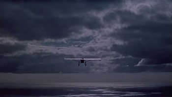 Movie still from “The Spirit of St. Louis” (1957), directed by Billy Wilder – An airplane is flying in the sky on a cloudy day; Extreme Wide shot, Low angle
