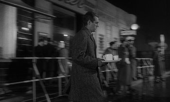 Movie still from “The Spy Who Came in from the Cold” (1965), directed by Martin Ritt – A black and white photo of a man walking down the street holding a tray; Wide shot, High angle