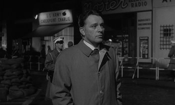 Movie still from “The Spy Who Came in from the Cold” (1965), directed by Martin Ritt – A black and white photo of a man in a trench coat; Medium shot, Low angle