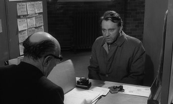 Movie still from “The Spy Who Came in from the Cold” (1965), directed by Martin Ritt – A man sitting at a table in front of another man; Medium shot, Over the shoulder angle