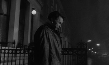 Movie still from “The Spy Who Came in from the Cold” (1965), directed by Martin Ritt – A black and white photo of a man standing outside; Medium shot, Low angle