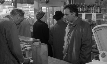 Movie still from “The Spy Who Came in from the Cold” (1965), directed by Martin Ritt – A group of people standing around a counter; Medium shot, Over the shoulder angle