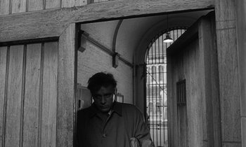 Movie still from “The Spy Who Came in from the Cold” (1965), directed by Martin Ritt – A black and white photo of a man standing in a doorway; Medium shot, Low angle