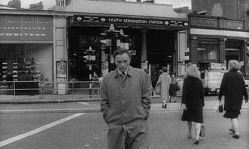Movie still from “The Spy Who Came in from the Cold” (1965), directed by Martin Ritt – A black and white photo of a man standing in front of a train station; Medium shot, Low angle