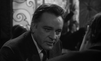 Movie still from “The Spy Who Came in from the Cold” (1965), directed by Martin Ritt – Black and white photograph of a man in a suit and tie; Close Up shot, Over the shoulder angle